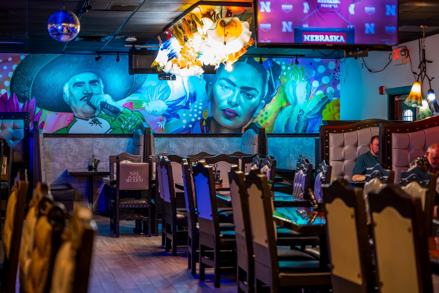 Colorful restaurant interior with mural art, empty tables, and chairs.