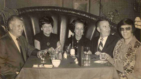 A black and white photo of a group of people sitting at a table.