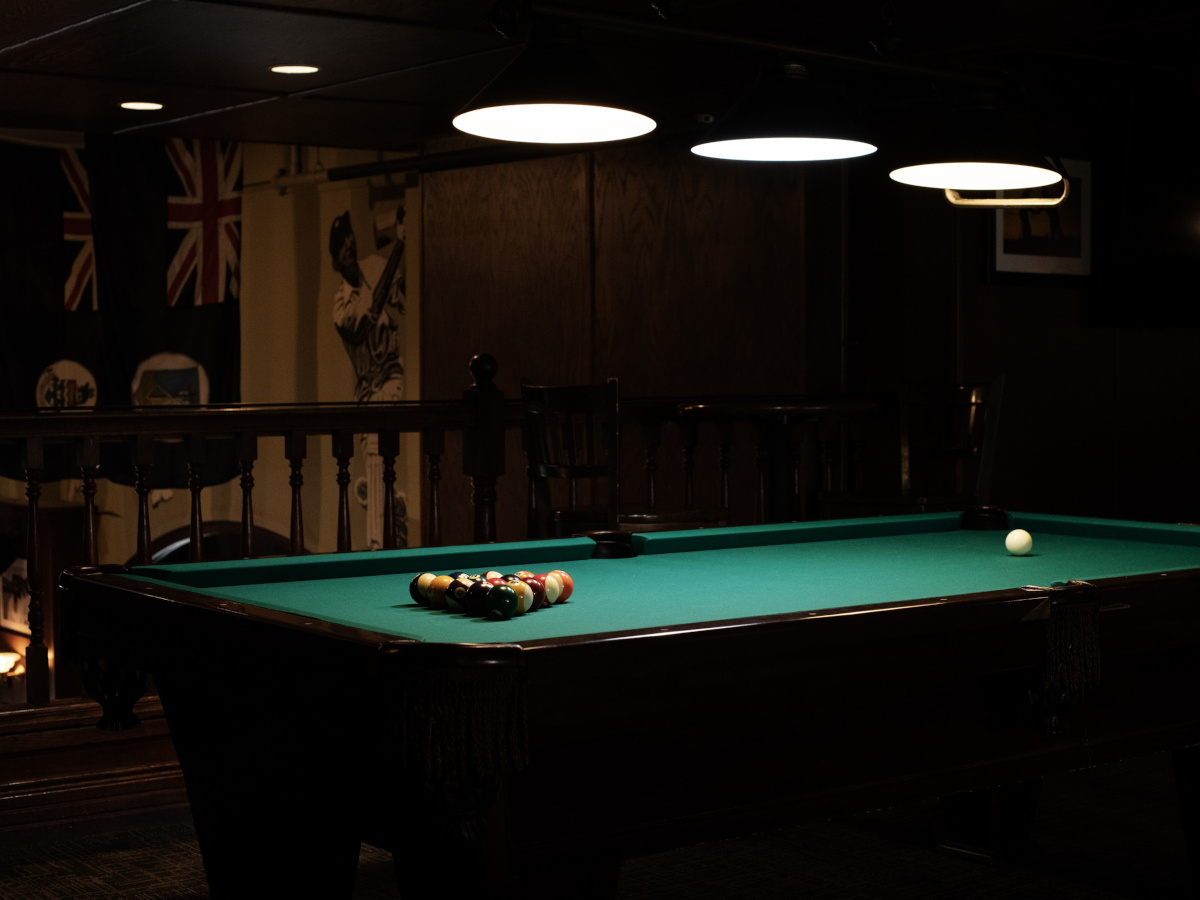 Billiards table with racked balls under overhead lights