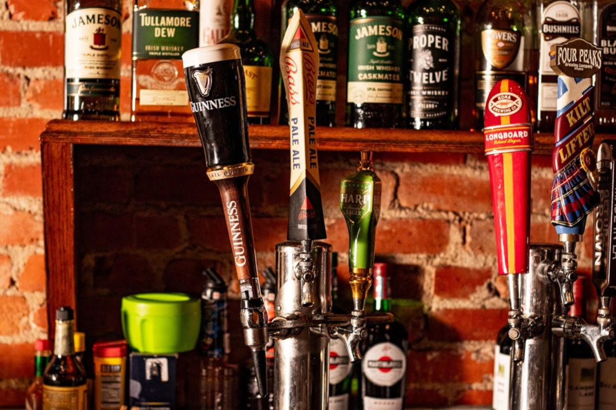 Beer taps and bottles on a bar shelf.