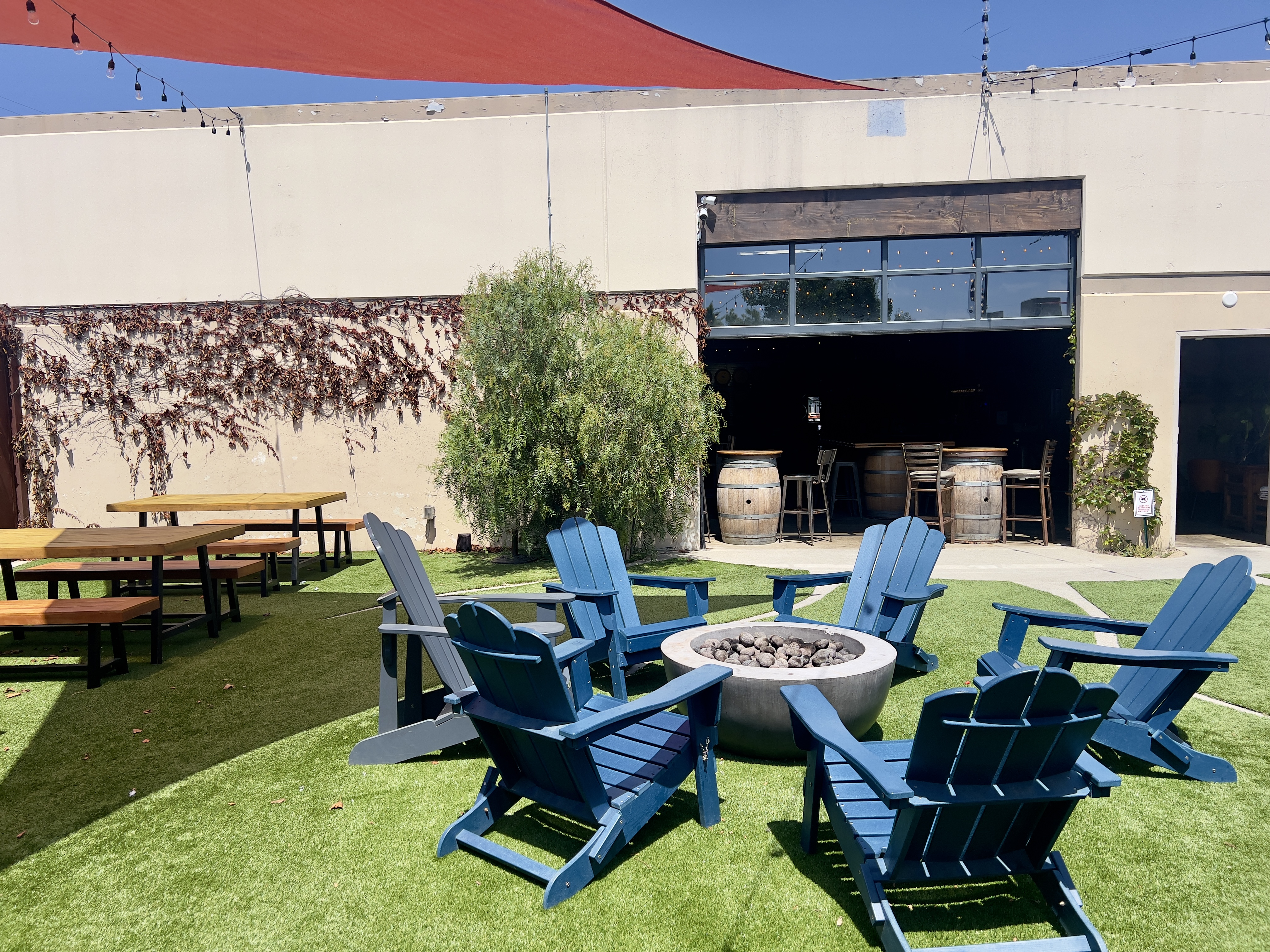 Outdoor patio with blue chairs around a fire pit.