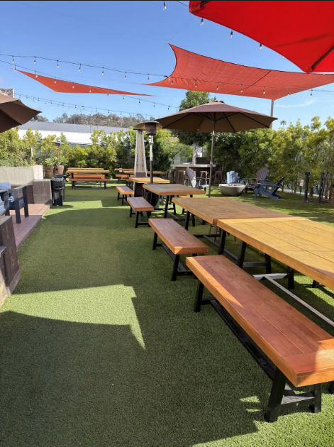 Picnic tables beneath red shade sails on patio.