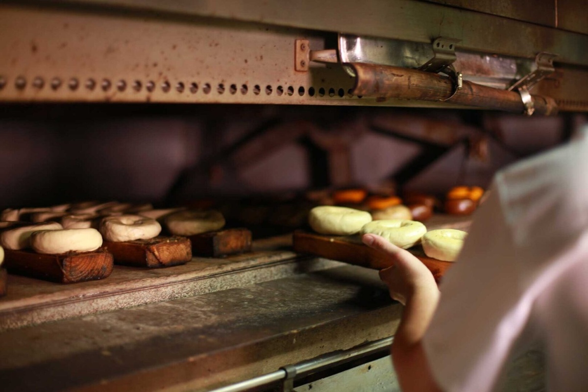 A baker is putting bread into an oven.