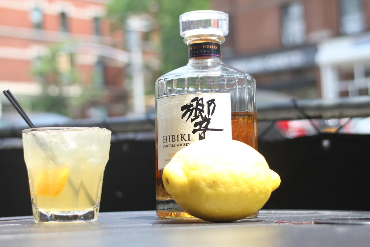 Yellow cocktail, a lemon and a bottle of suntory whiskey