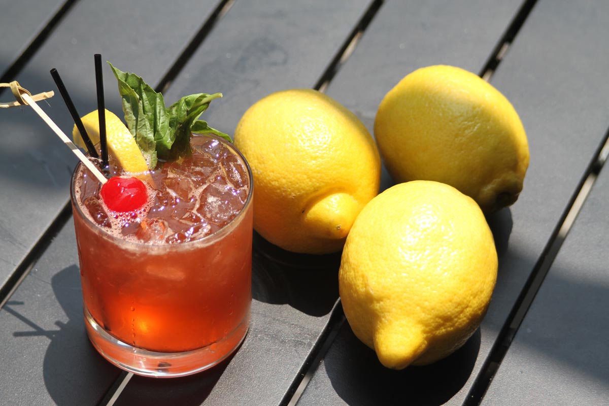 Deep orange cocktail with decorations and three lemons