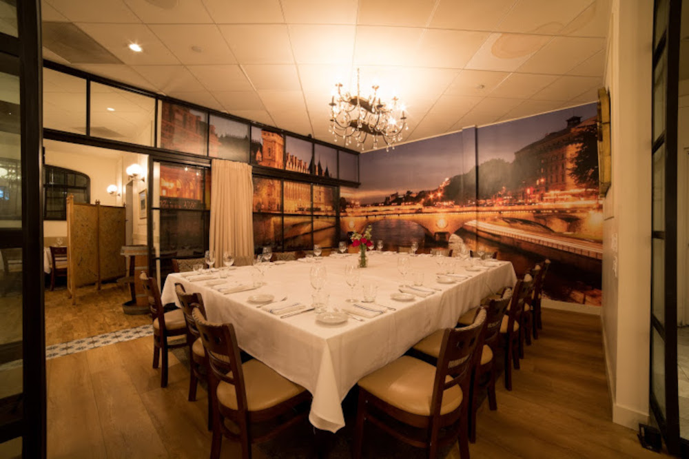 Dining area with large wall mural of a night cityscape and a chandelier.
