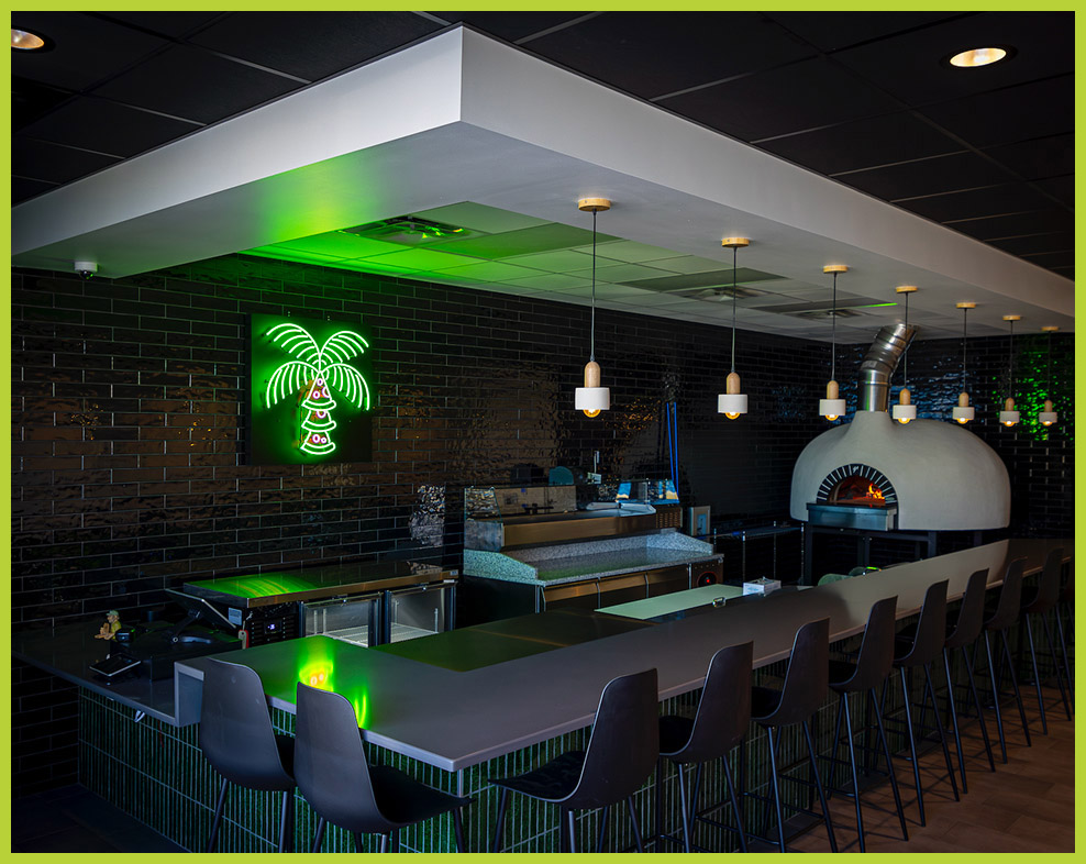 Sour Street Pizza bar with a large pizza oven and a green neon palm tree.