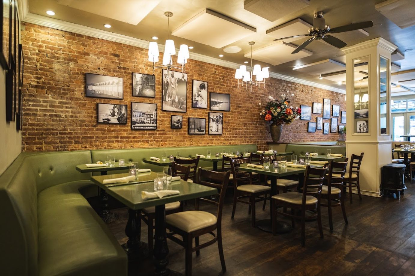 Banquette seating with tables and chairs, framed old pictures on a brick wall
