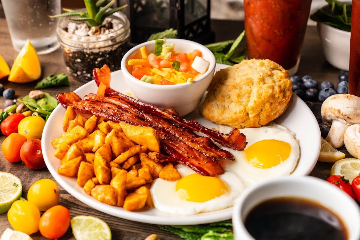 A plate of breakfast food with bacon, eggs and tomatoes.