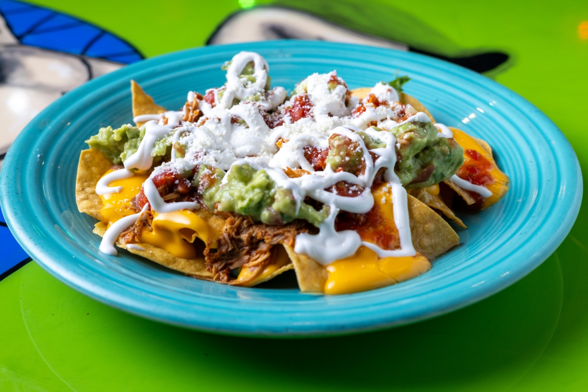 Plate of nachos with toppings on a turquoise dish