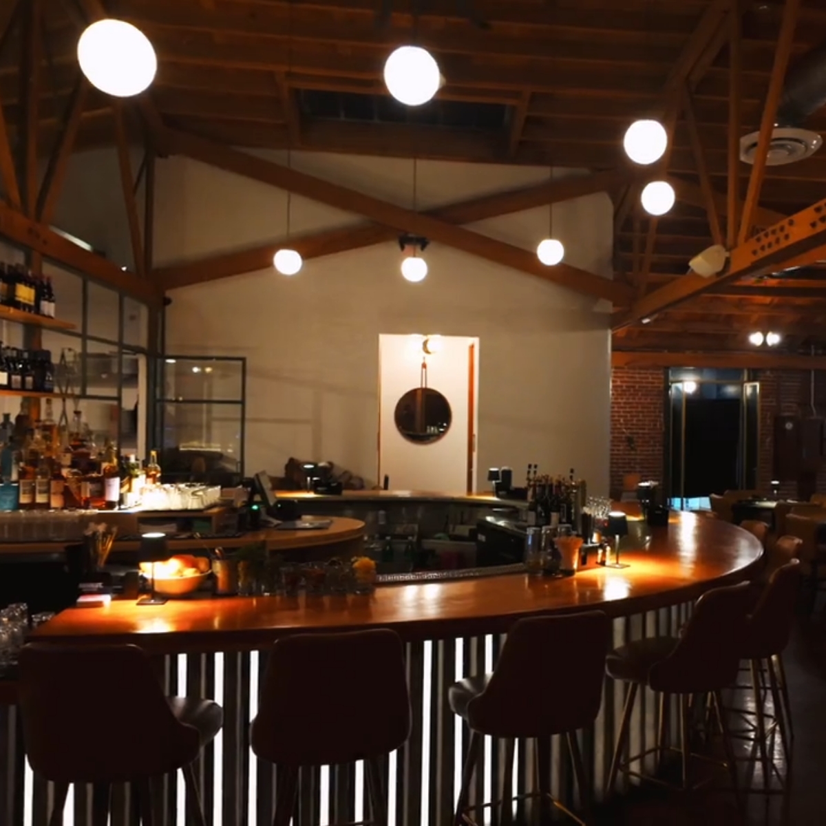 A bar featuring a long counter with several chairs arranged along one side.