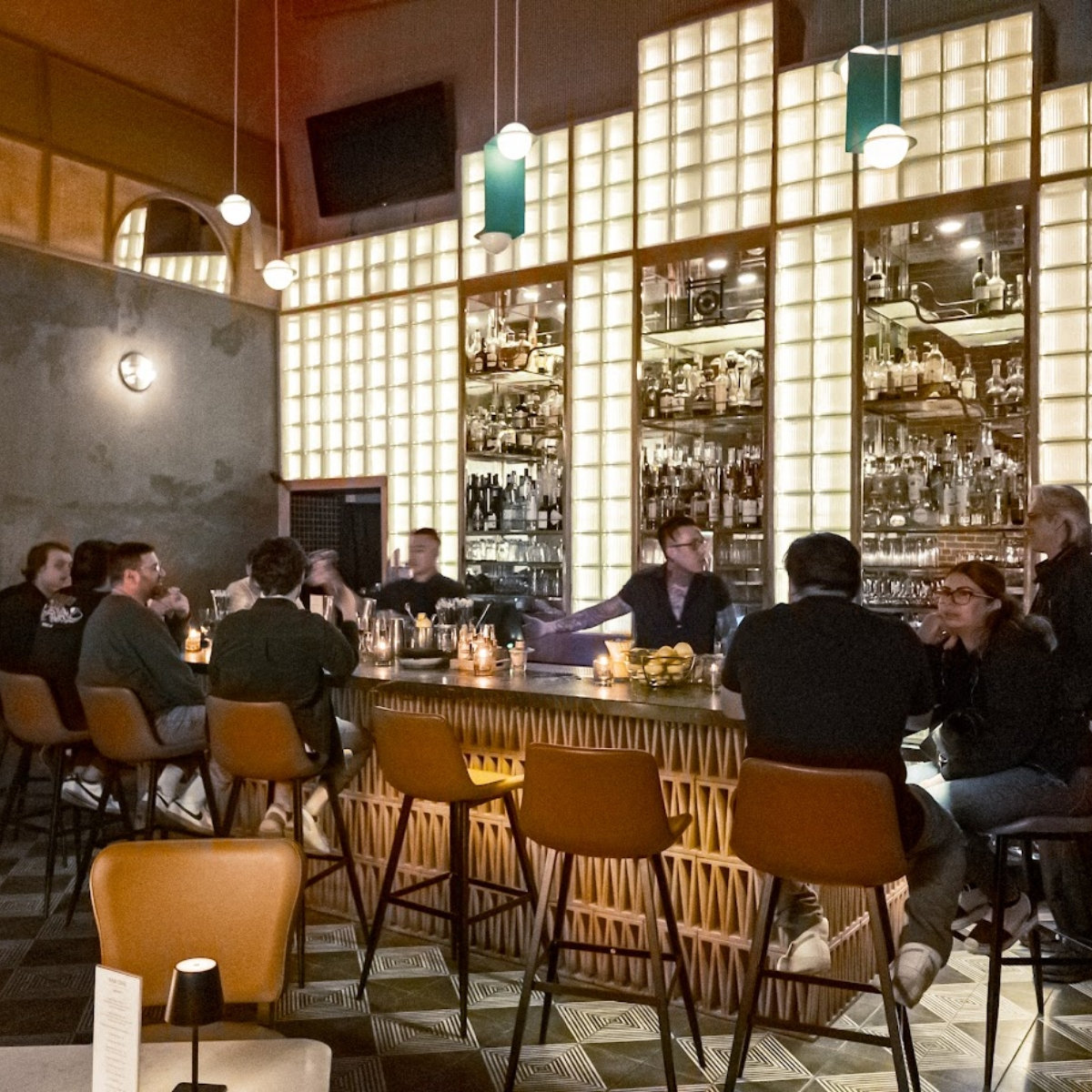A group of people seated at a bar, enjoying drinks and conversation in a cozy atmosphere.