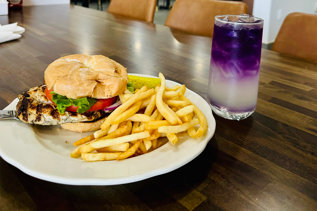 Chicken burger served with fries, alongside a cocktail