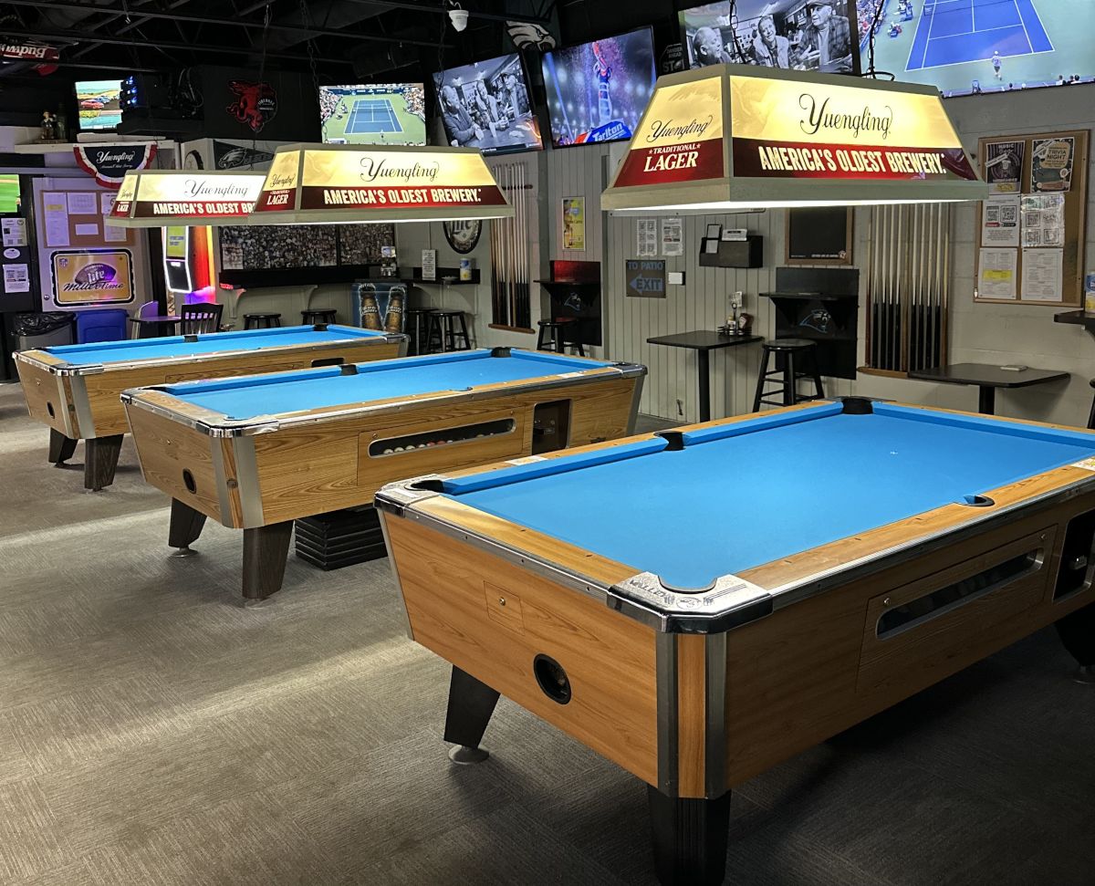 A billiards room with several tables and televisions.