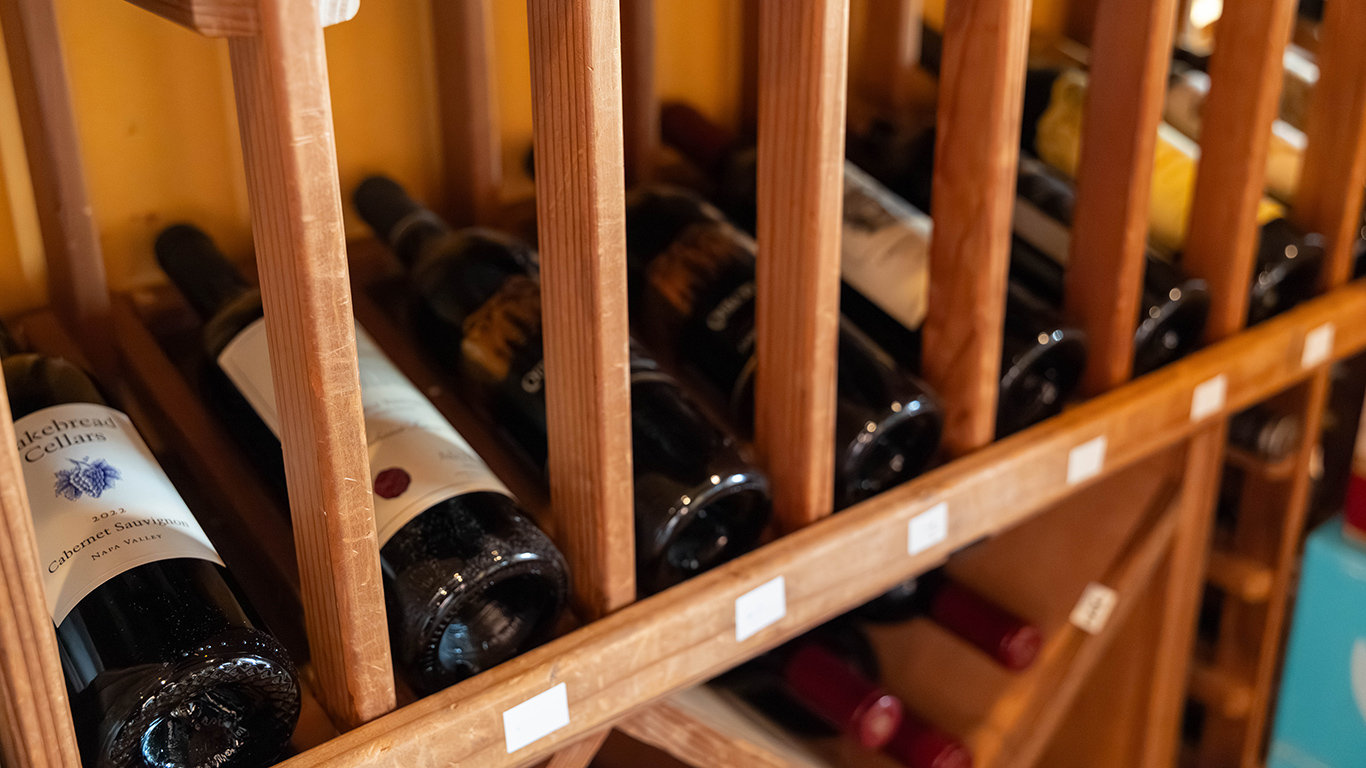 Close-up of wine bottles in wooden rack, including 2022 Napa Valley Cabernet