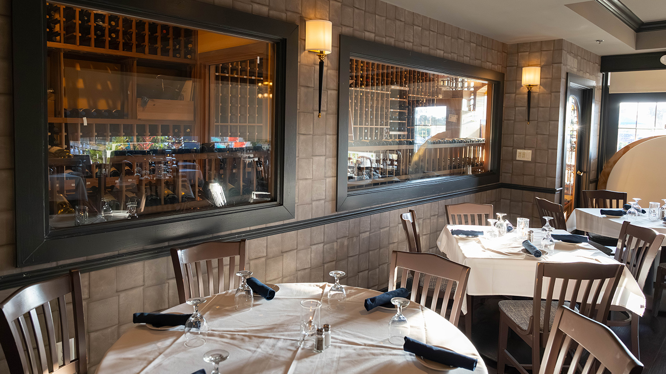 Restaurant dining room with stone walls and wine cellar visible through windows