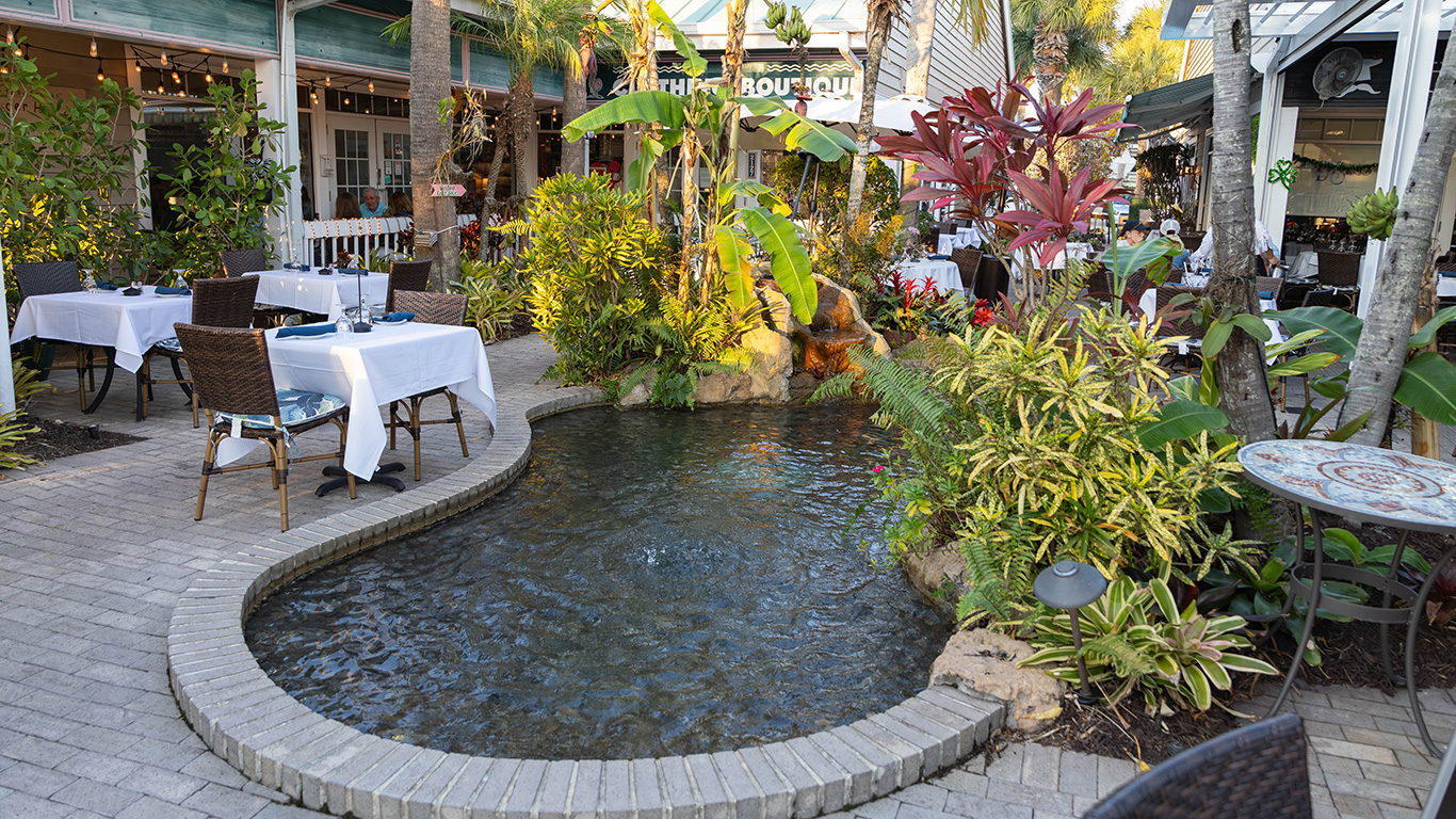 Outdoor restaurant patio with koi pond surrounded by tropical plants