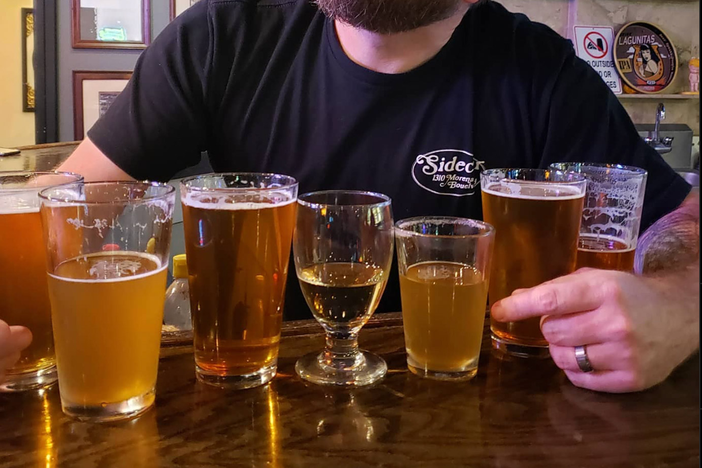 Various glasses of beer with a person sitting behind