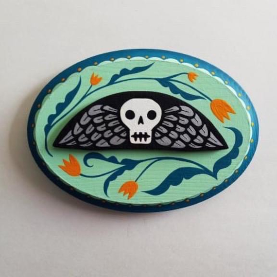 Painted oval object with a skull and wings