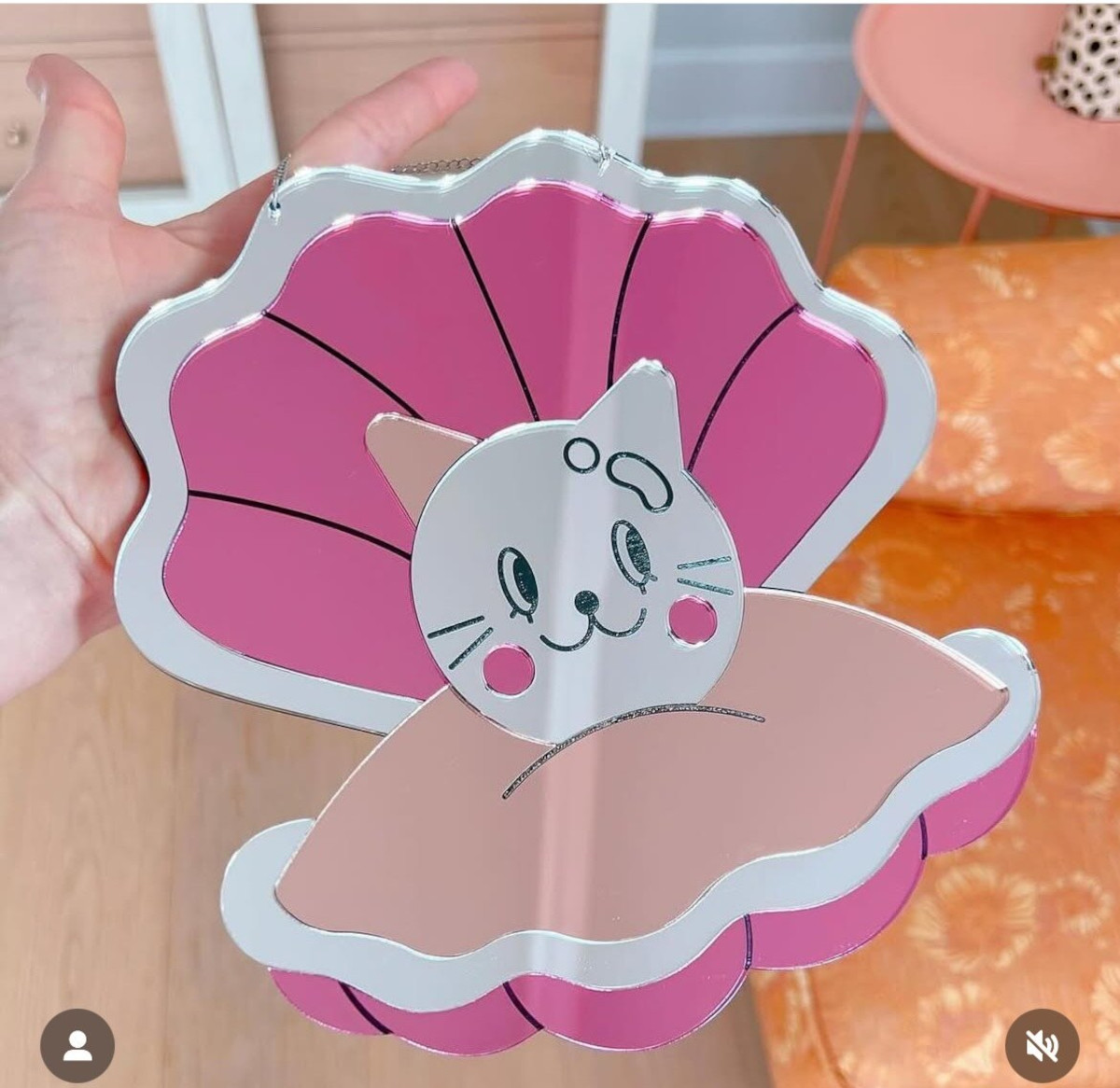 a person holds a pink shell-shaped cat illustration