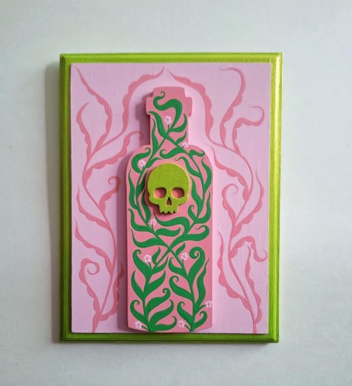 A pink and green bottle with a skull design