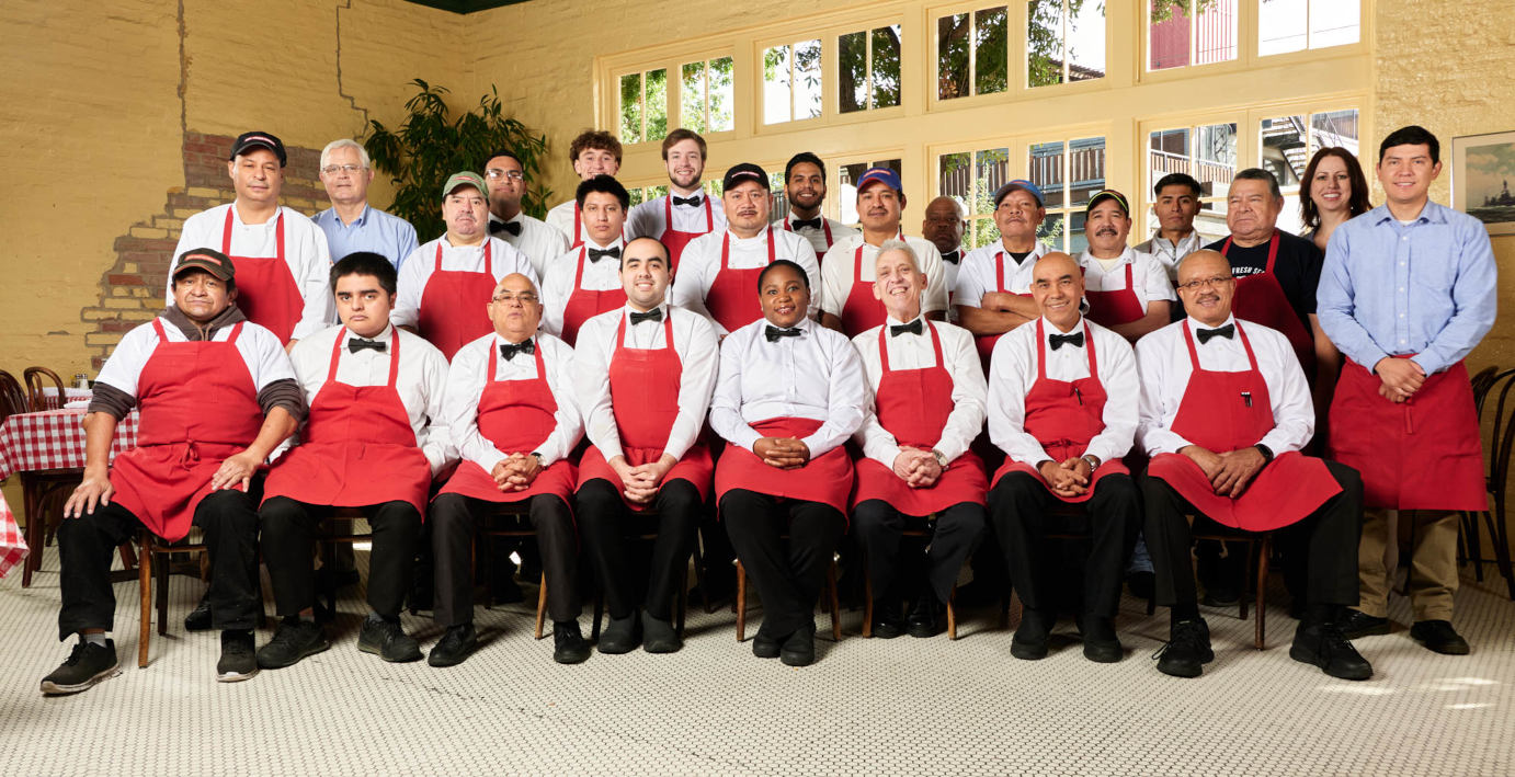 A group of people in red aprons posing for a photo.