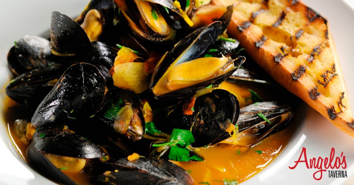 Mussels in savory sauce with bread on a plate.