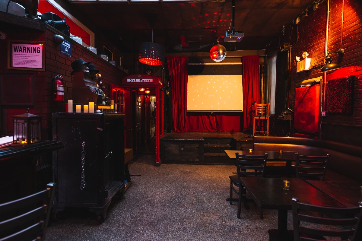 a dimly lit room with red curtains and tables