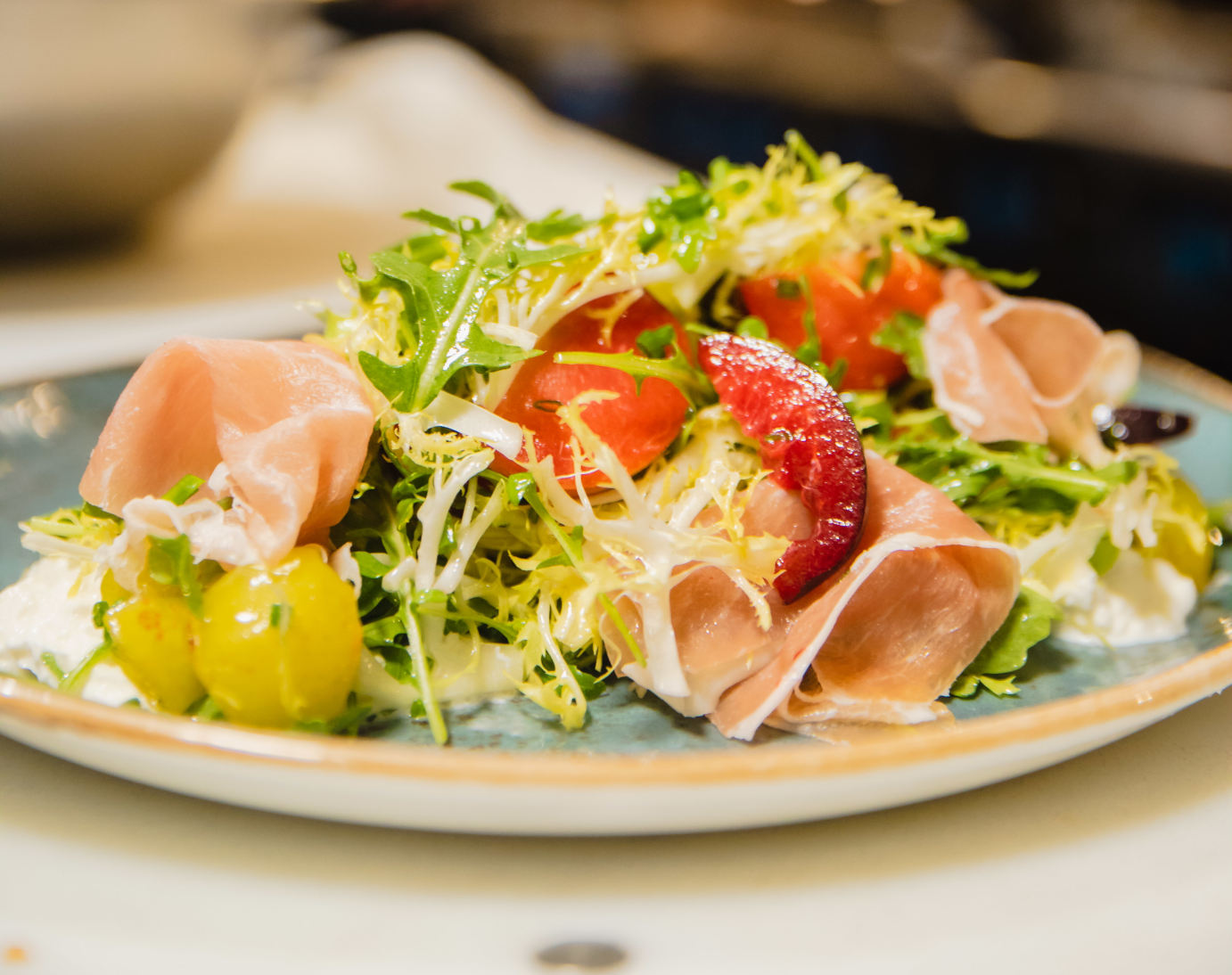 Gourmet prosciutto and fig salad with fresh tomatoes on a rustic plate.