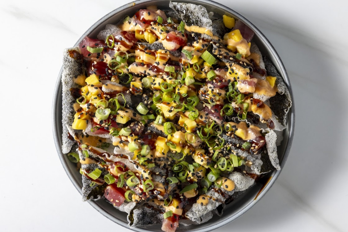 Close-up of loaded tortilla chips topped with green onions and diced vegetables