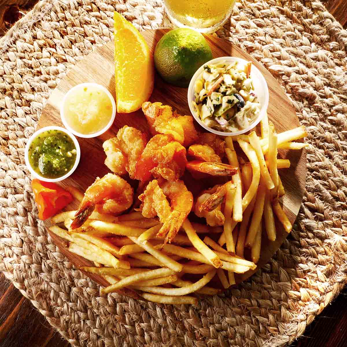 Fried crawfish with fries, sauces, citrus slices and a salad, top view