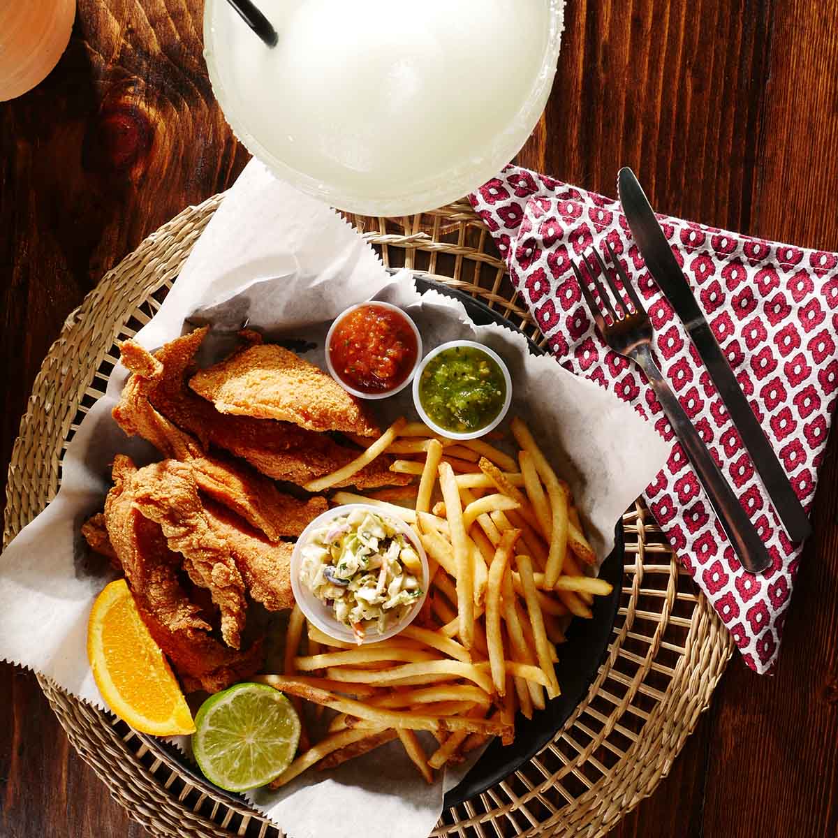 Fried fish and fries,with red and green salsa, citrus wedges and a salad