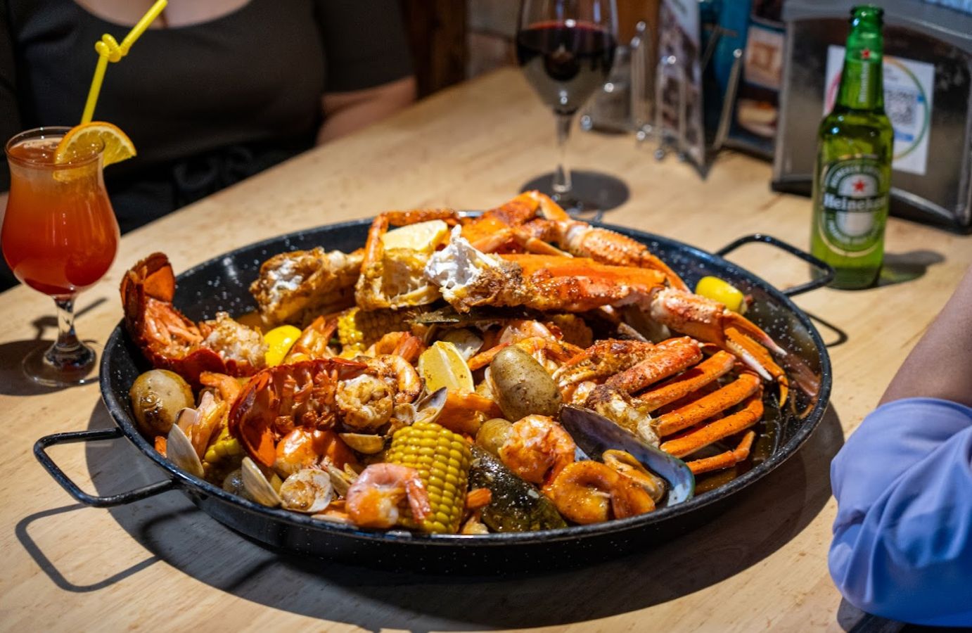 A large pan of seafood boil with crab legs, shrimp, corn, and mussels.