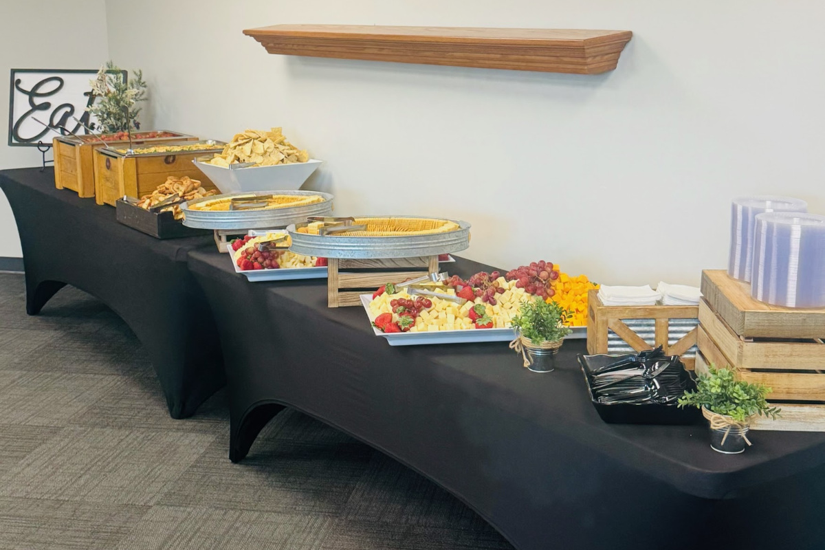 A banquet table with black cloth displays a variety of appetizers