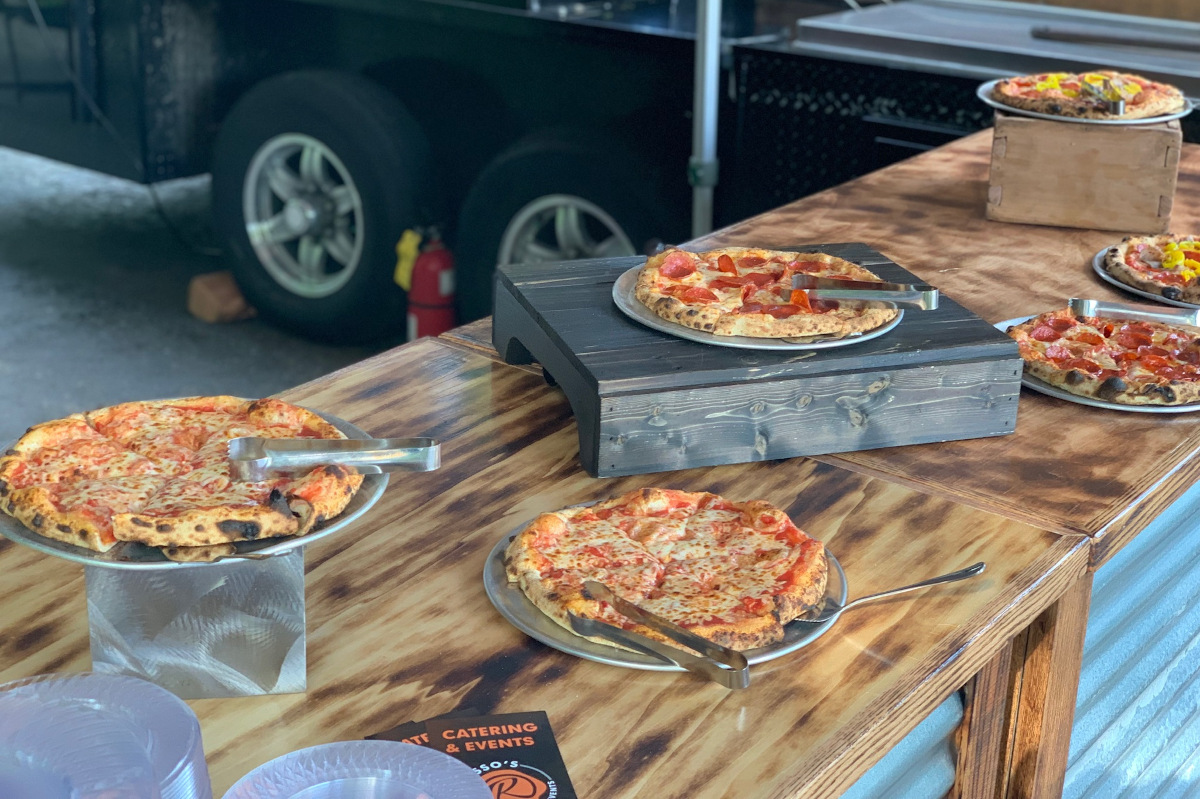 Assorted pizzas on stands and wooden trays set on a rustic table