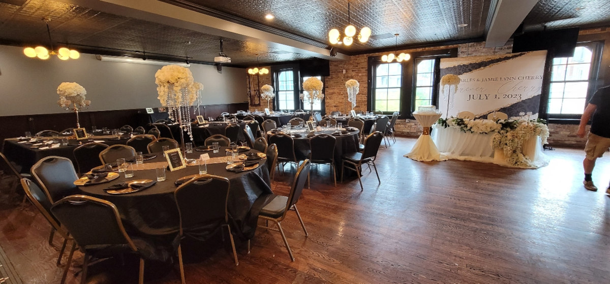 A room with tables and chairs set up for a wedding reception