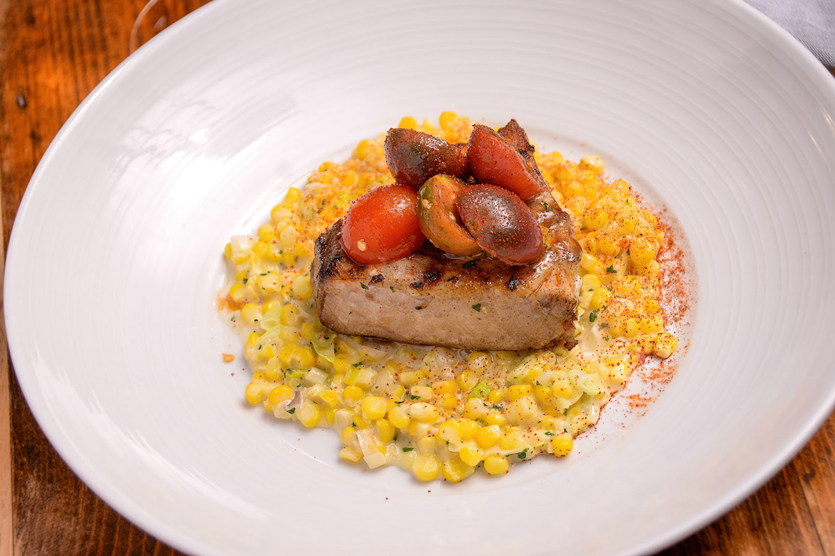 Pan-seared catfish, topped with cherry tomatoes, served over corn rissoto