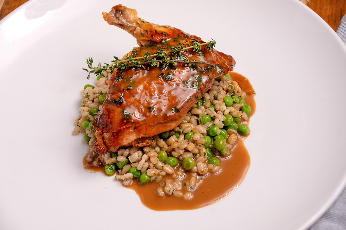 Roasted farm chicken breast served over rice and peas