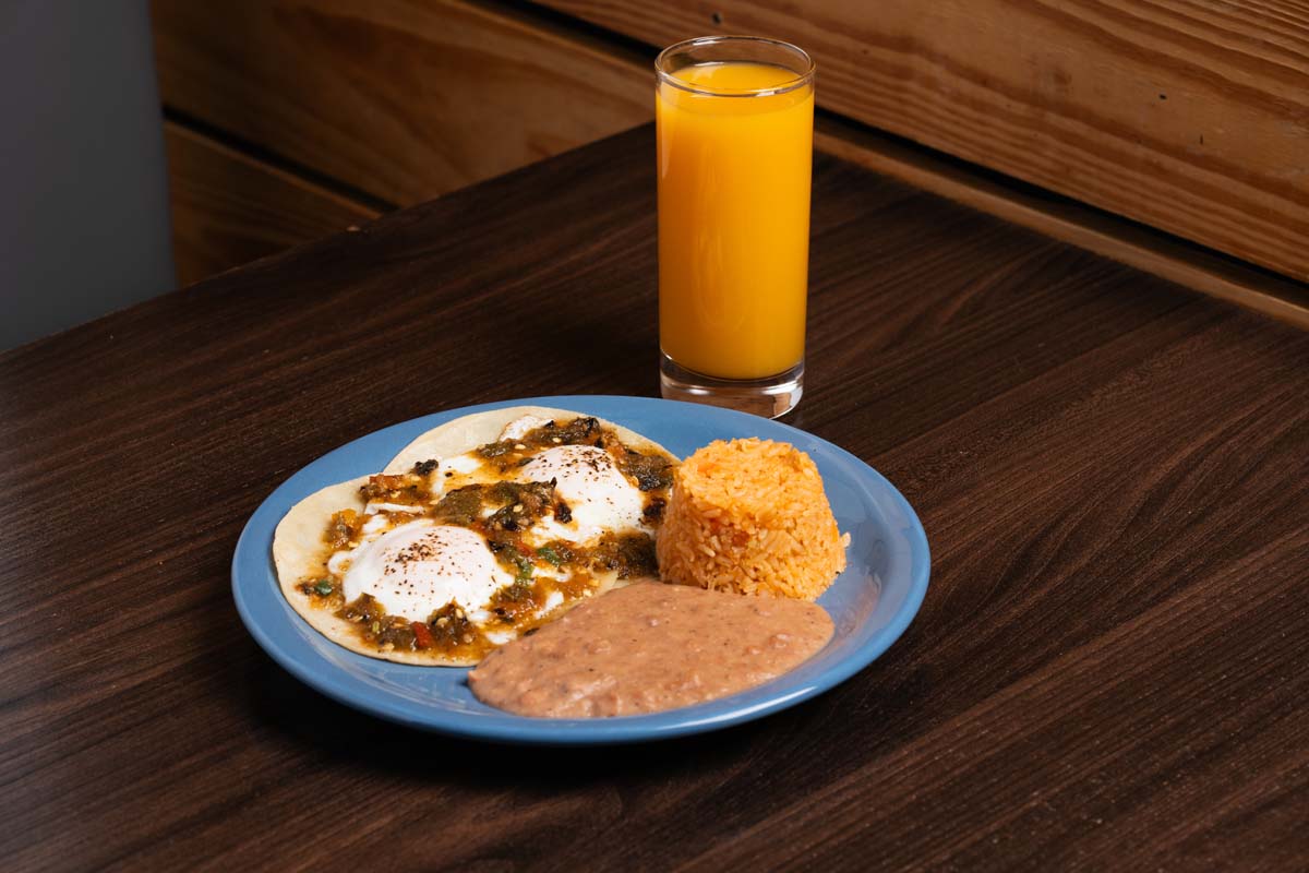 Huevos Rancheros, served on the blue plate, with glass filled with orange juice