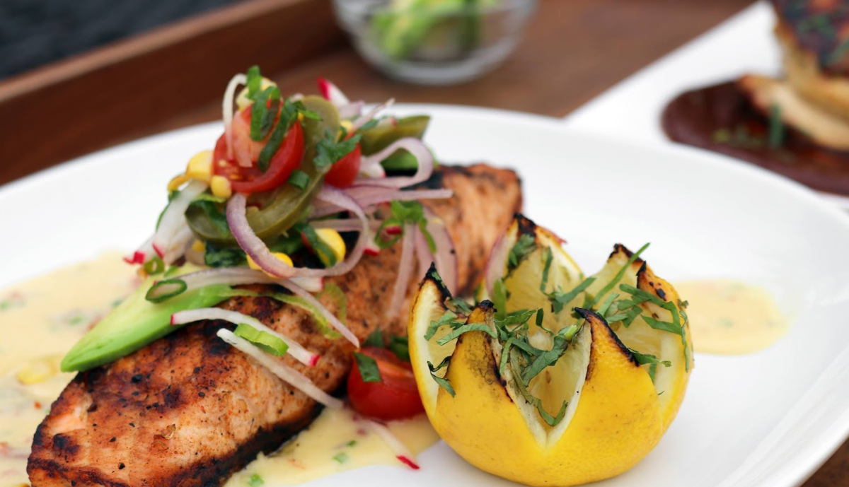 Grilled fish filet topped with mixed salad, served with a lemon