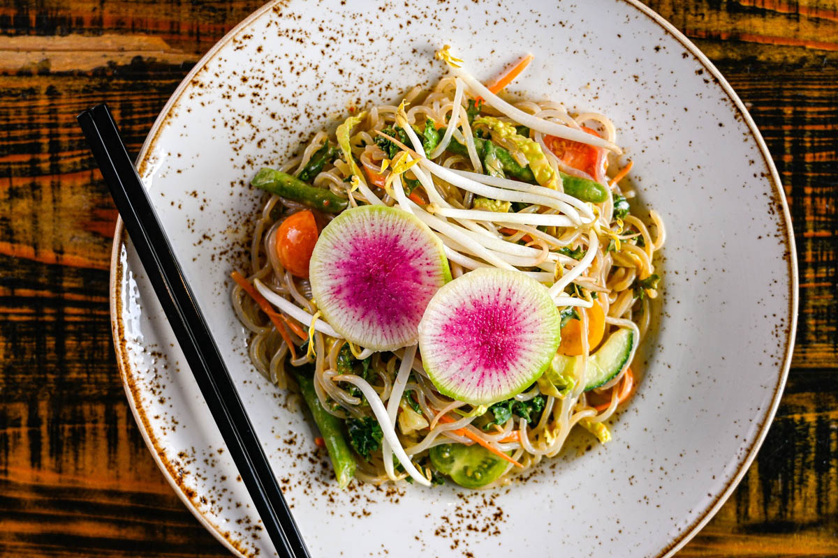 Noodle dish with vegetables and sprouts, topped with radish