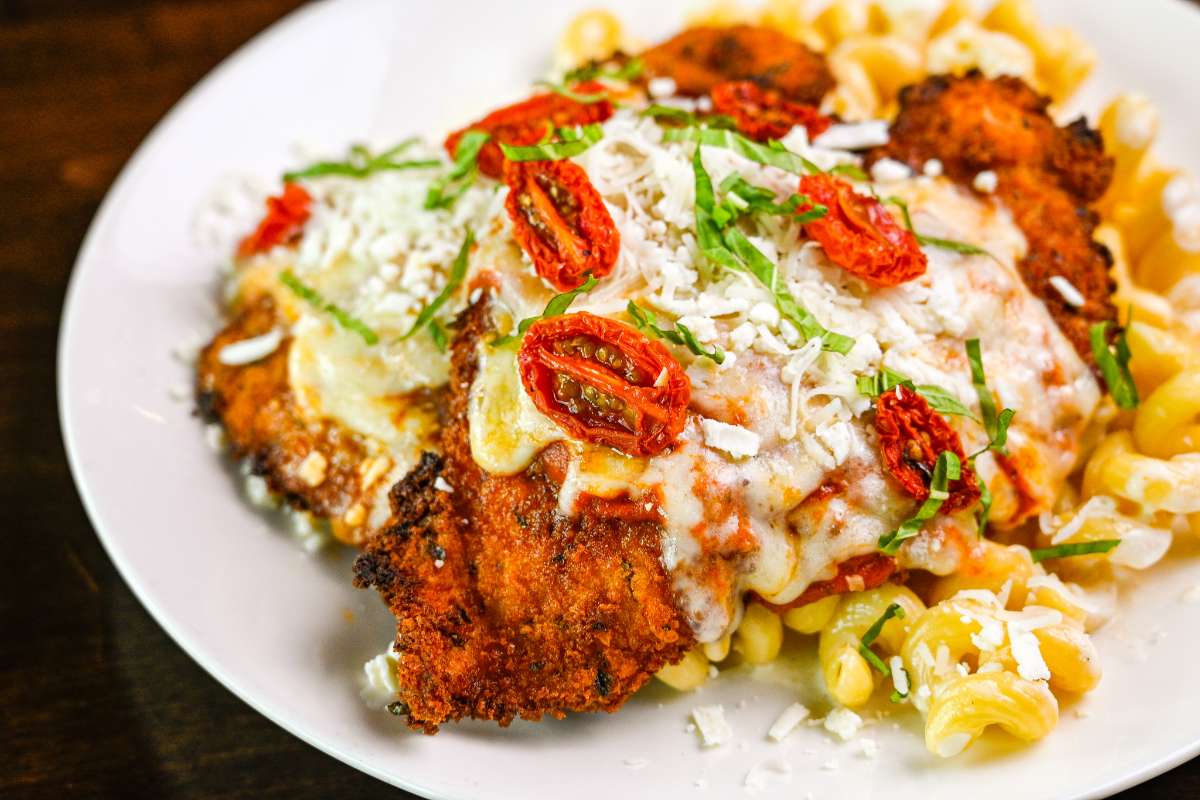 Fried chicken topped with cheese and sun-dried cherry tomatoes, served over macaroni