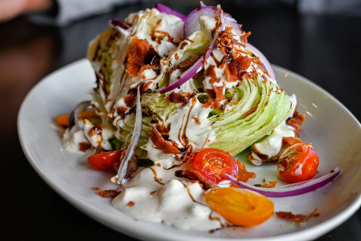 Wedge salad with bacon, white sauce, red onion and cherry tomatoes
