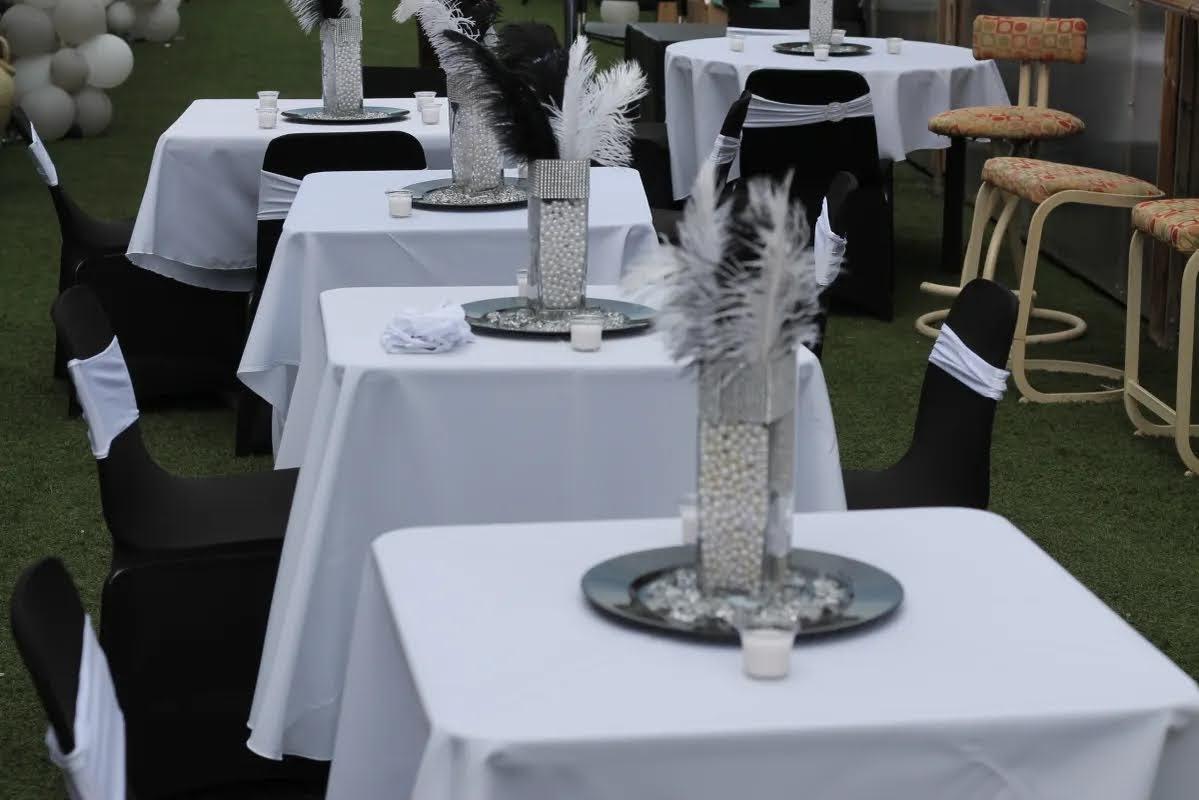 Lined up tables with white table cloths and decorative vases 