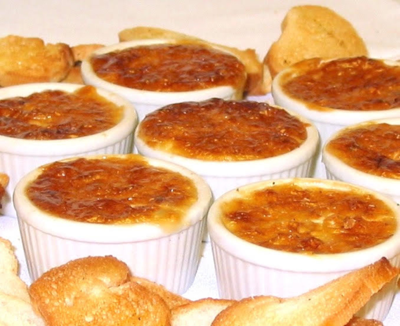 Small ramekins of caramelized crème brûlée served with bread slices