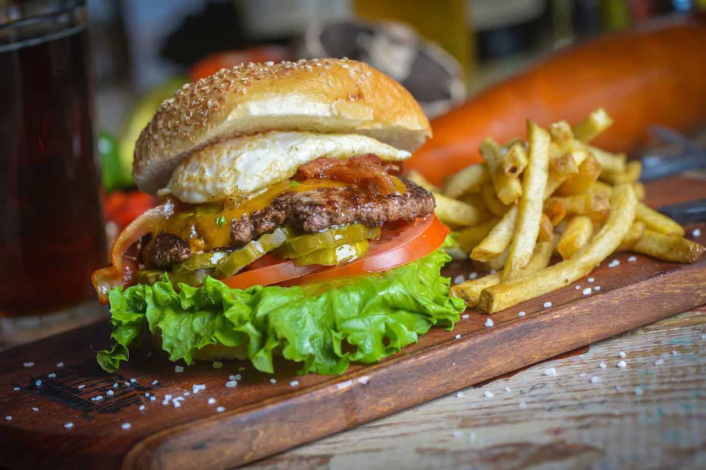 Burger with fried egg, bacon m pickle , tomato and lettuce, served with fries