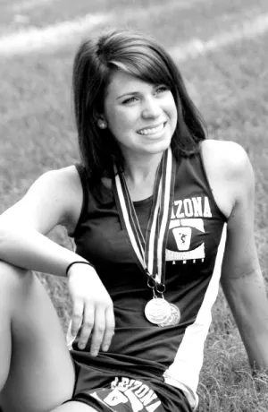 photograph of Sabrina resting on the ground in a sports outfit with a medal