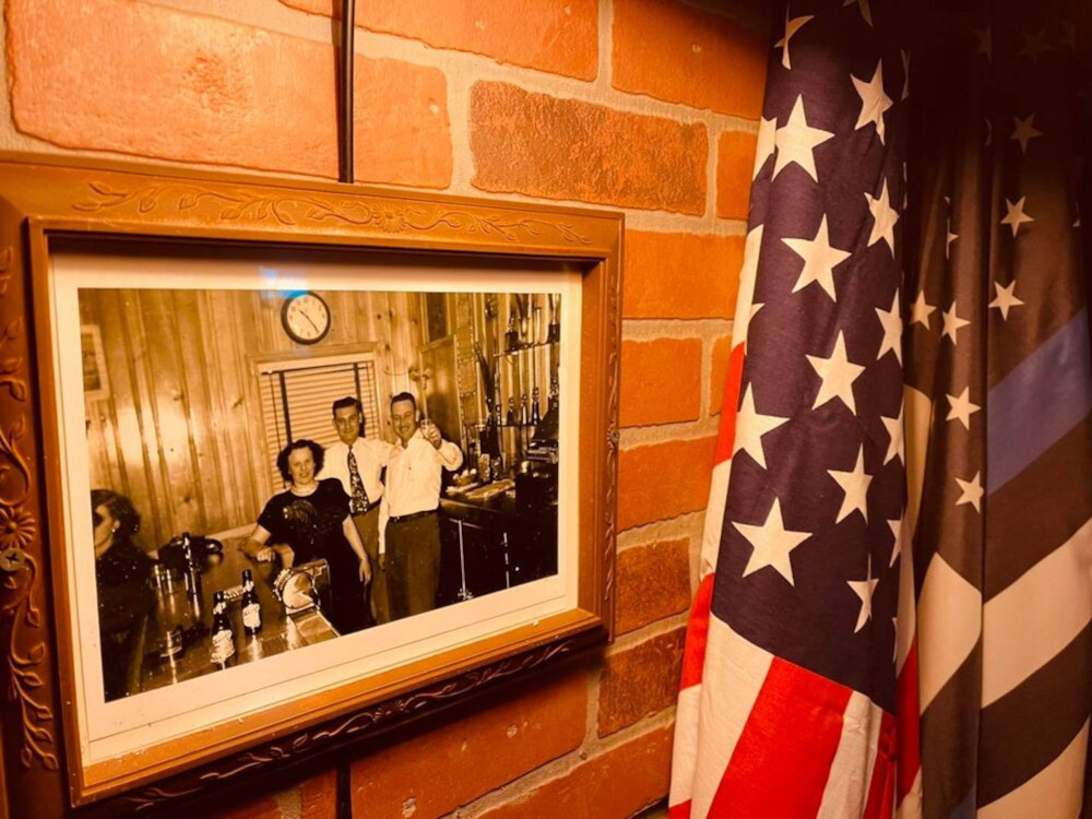 A framed photo and a flag on a brick wall.