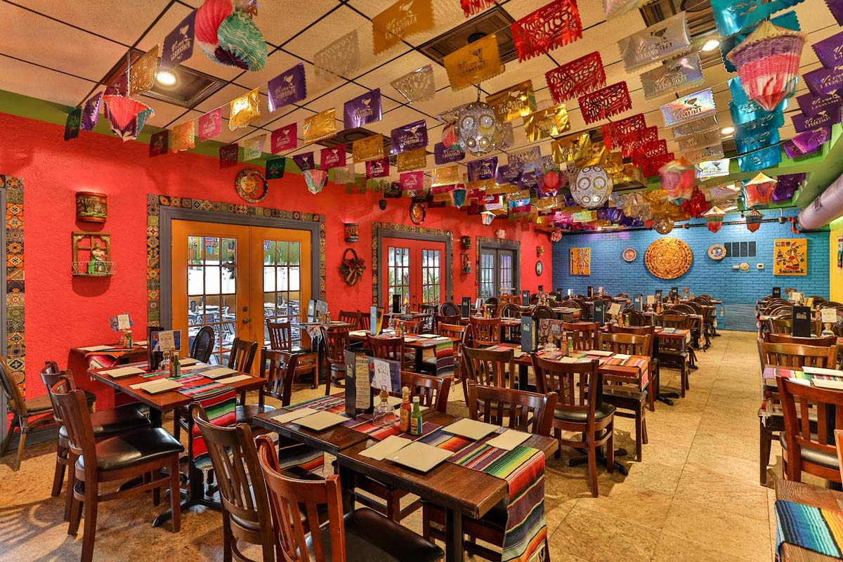 Dining area with lined up tables and lots of fiesta decorations on the ceiling 