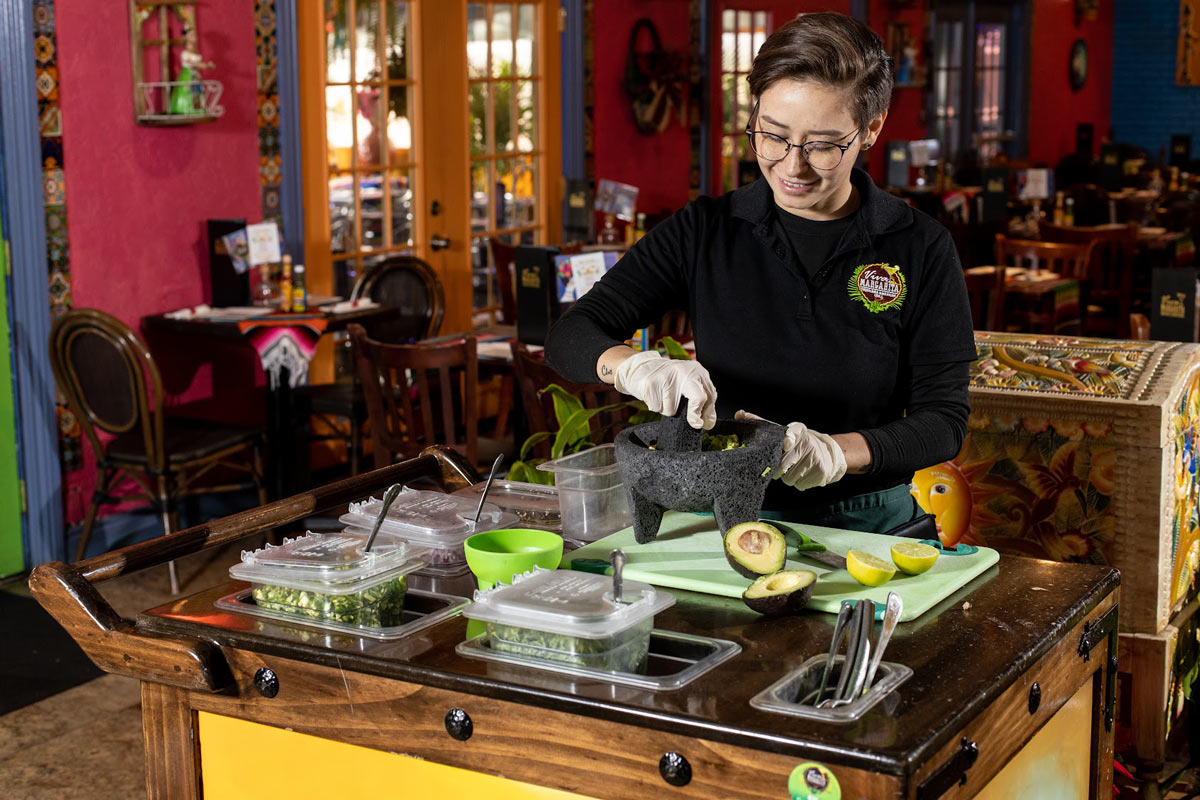 Employee preparing food at the guacamole station table